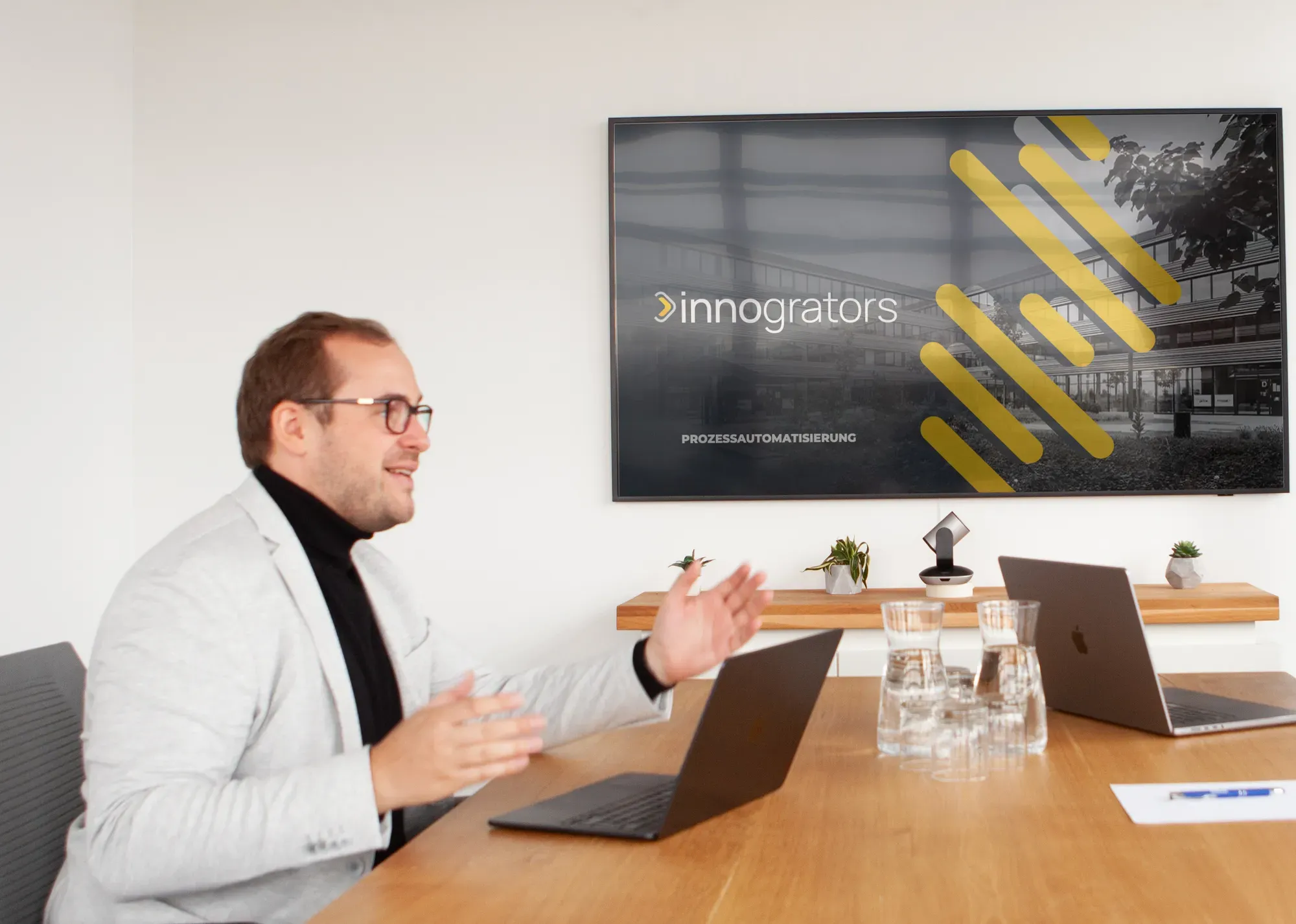 Philipp Köstner erklärt im Besprechungsraum ein Projekt zur Prozessautomatisierung, auf dem Bildschirm das innogrators-Logo