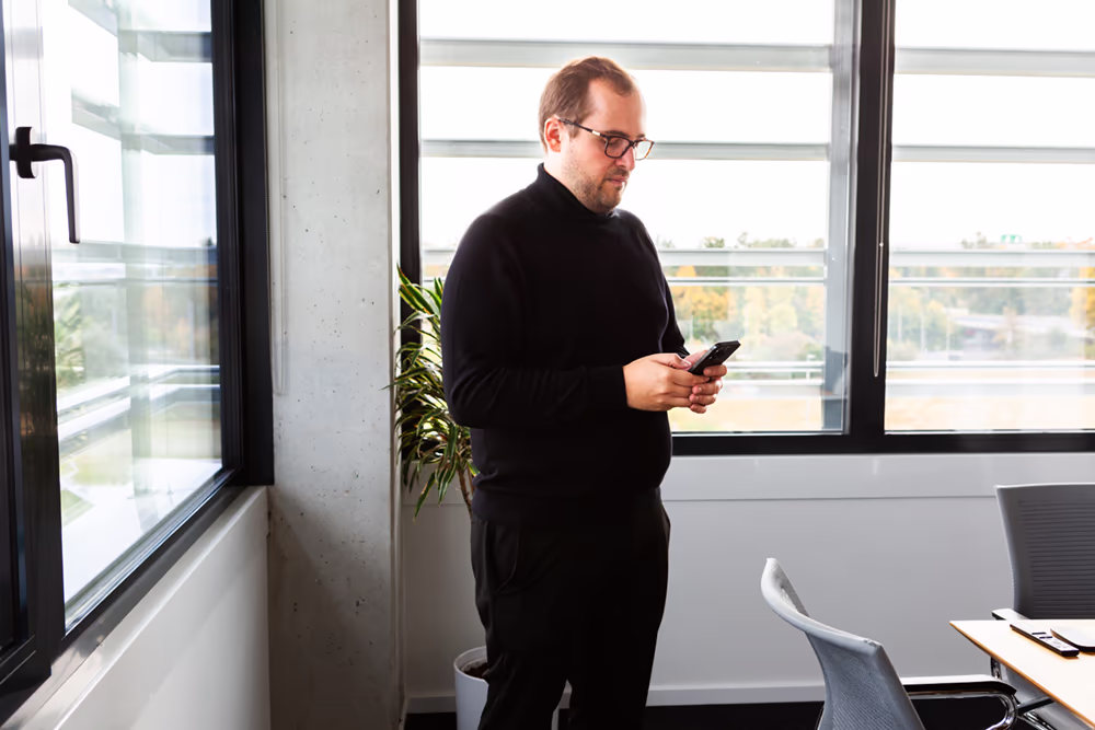Berater von innogrators am Fenster mit Smartphone